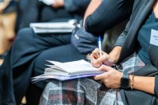 Audience member taking notes with a pen