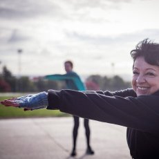 Woman over sixty stretching outside, smiling