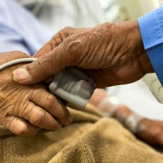 Hands with wrinkles holding each other at a hospital bed