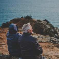 Two older people sitting by the seashore
