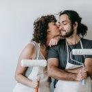 Young couple with paint rolls, kissing