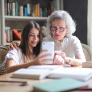 Older woman and young child look at mobile phone together