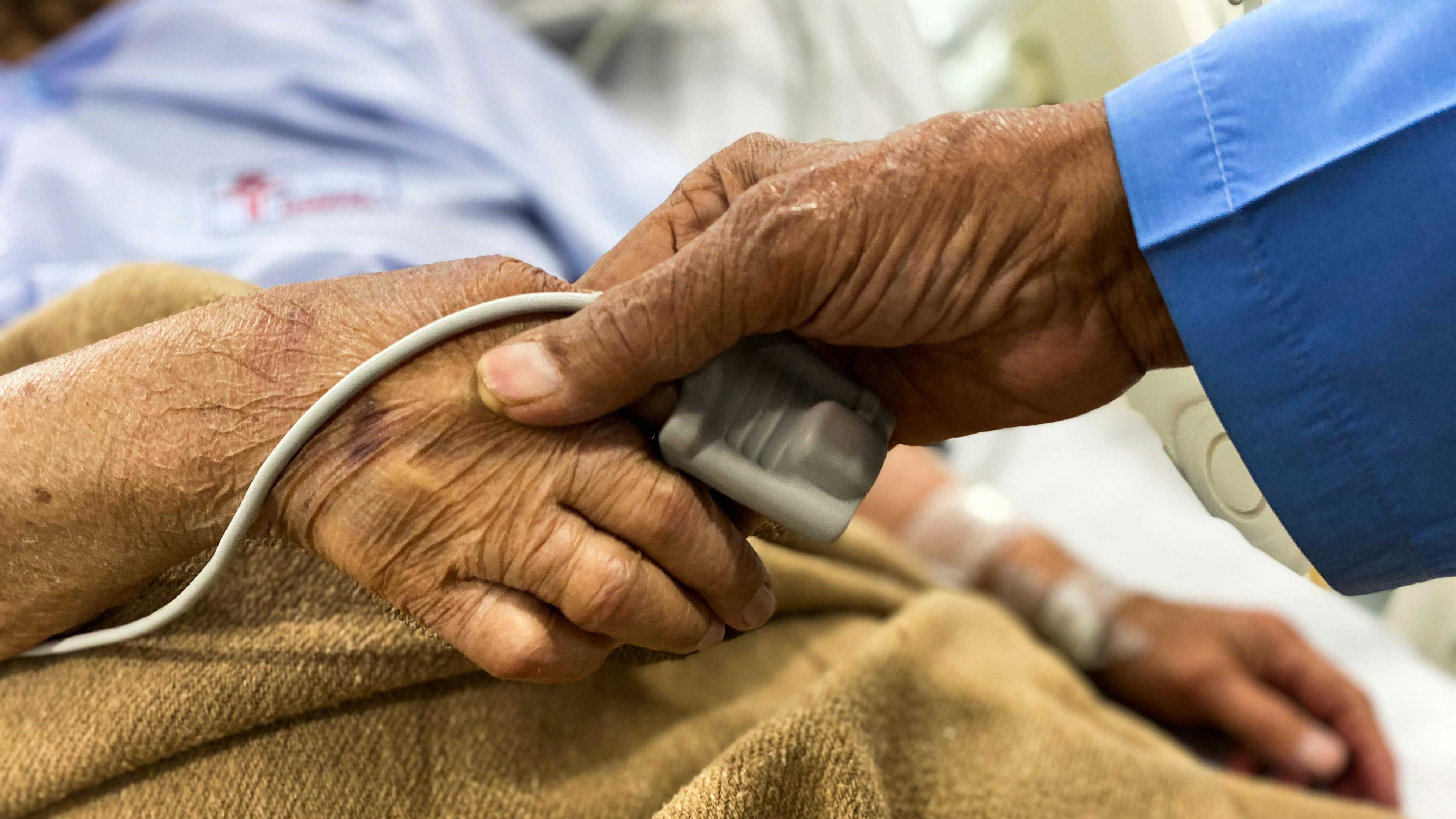 Hands with wrinkles holding each other at a hospital bed