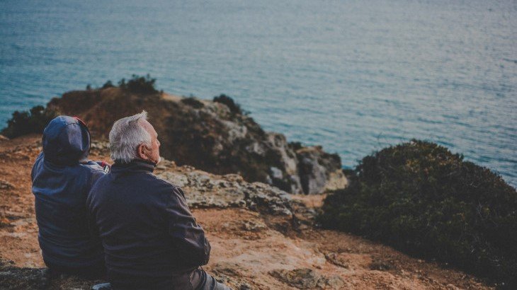 Two older people sitting by the seashore