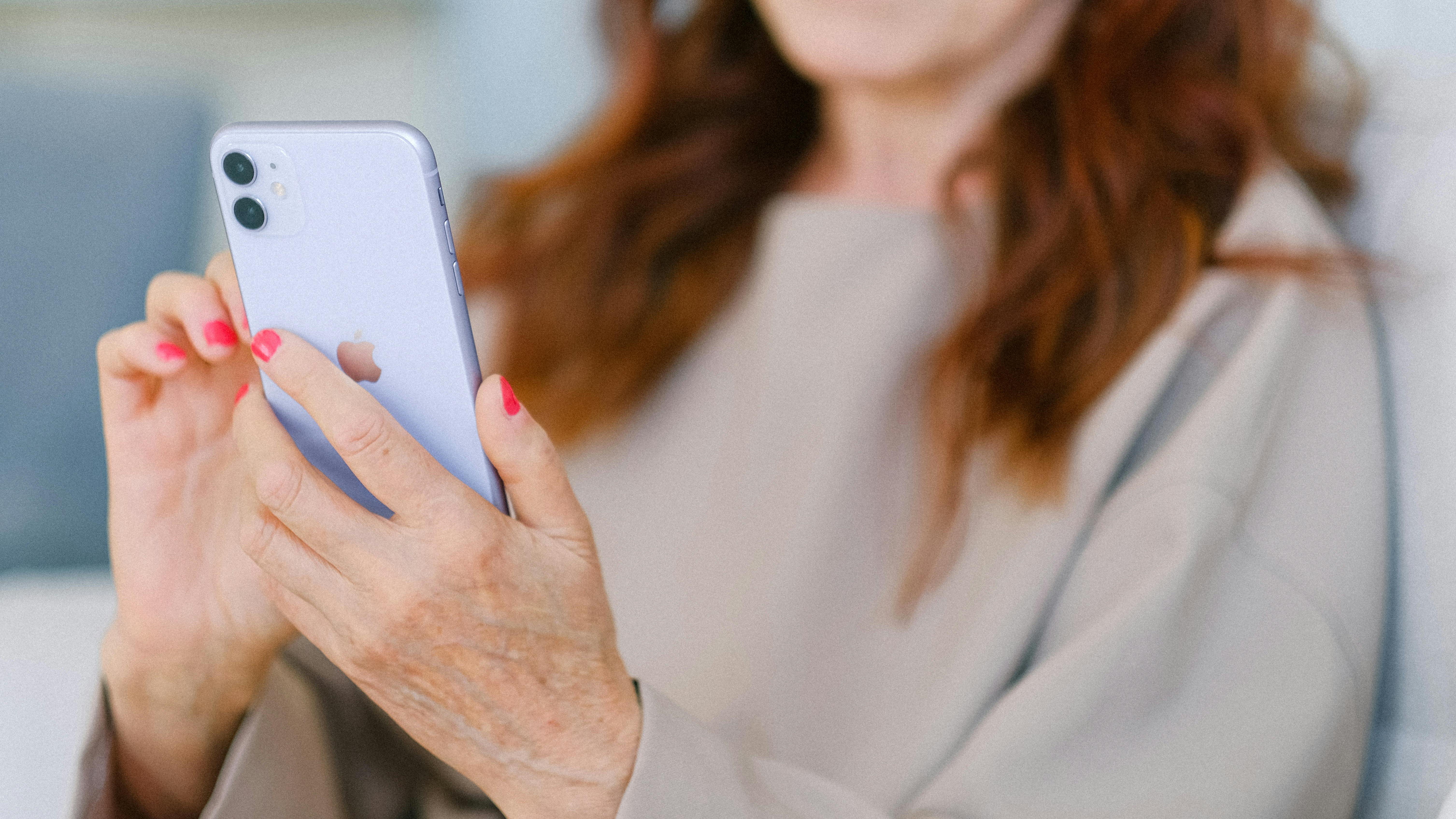 Older person with painted nails holds a mobile phone