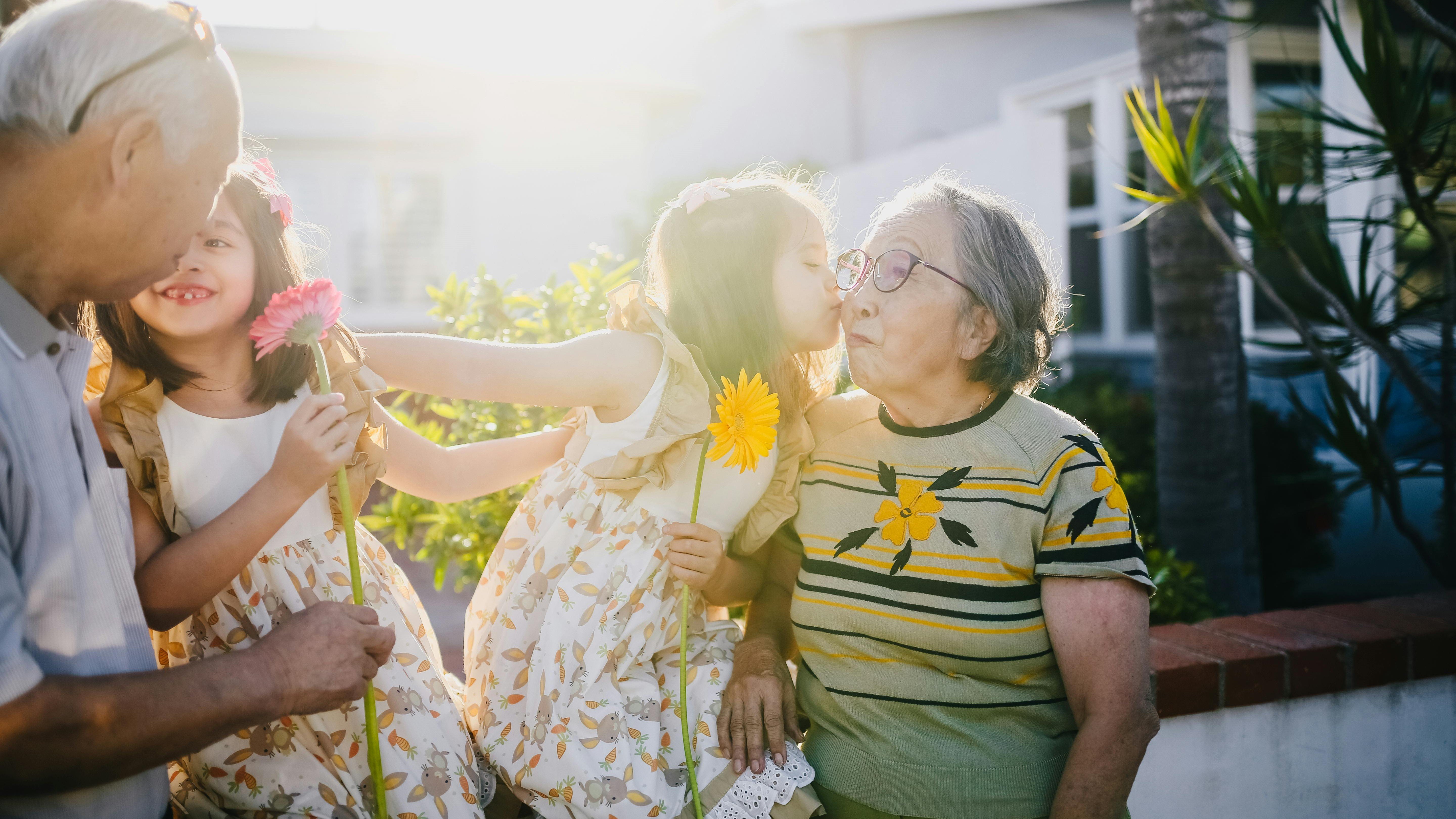 Older couple being greeted by two children with kisses on the cheek