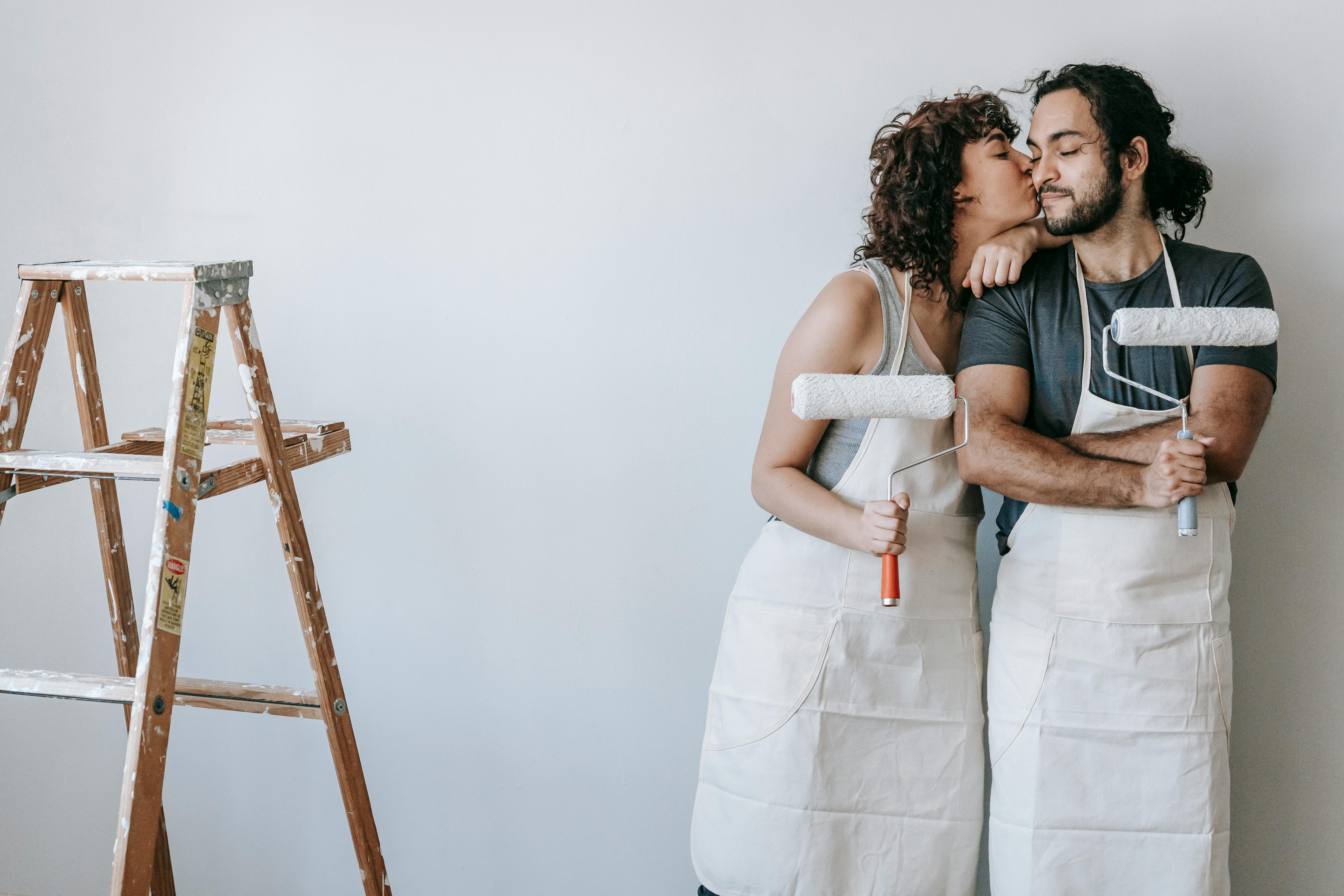 Young couple sharing a kiss while painting