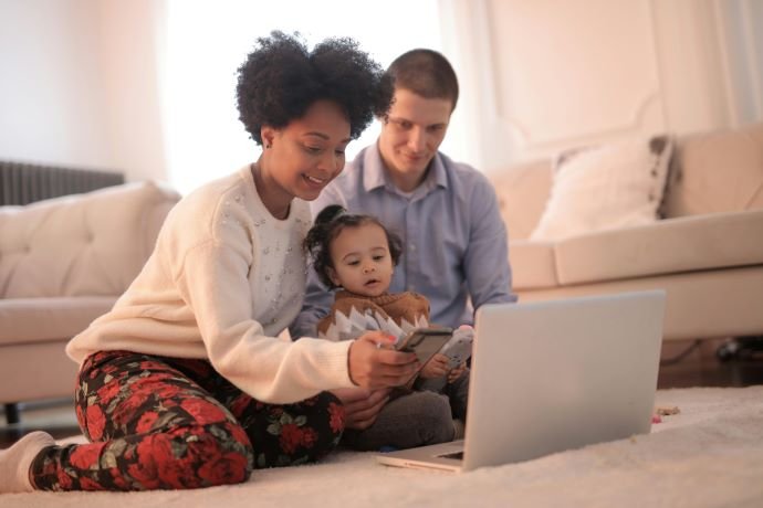 Parents and small child look at laptop and phone together